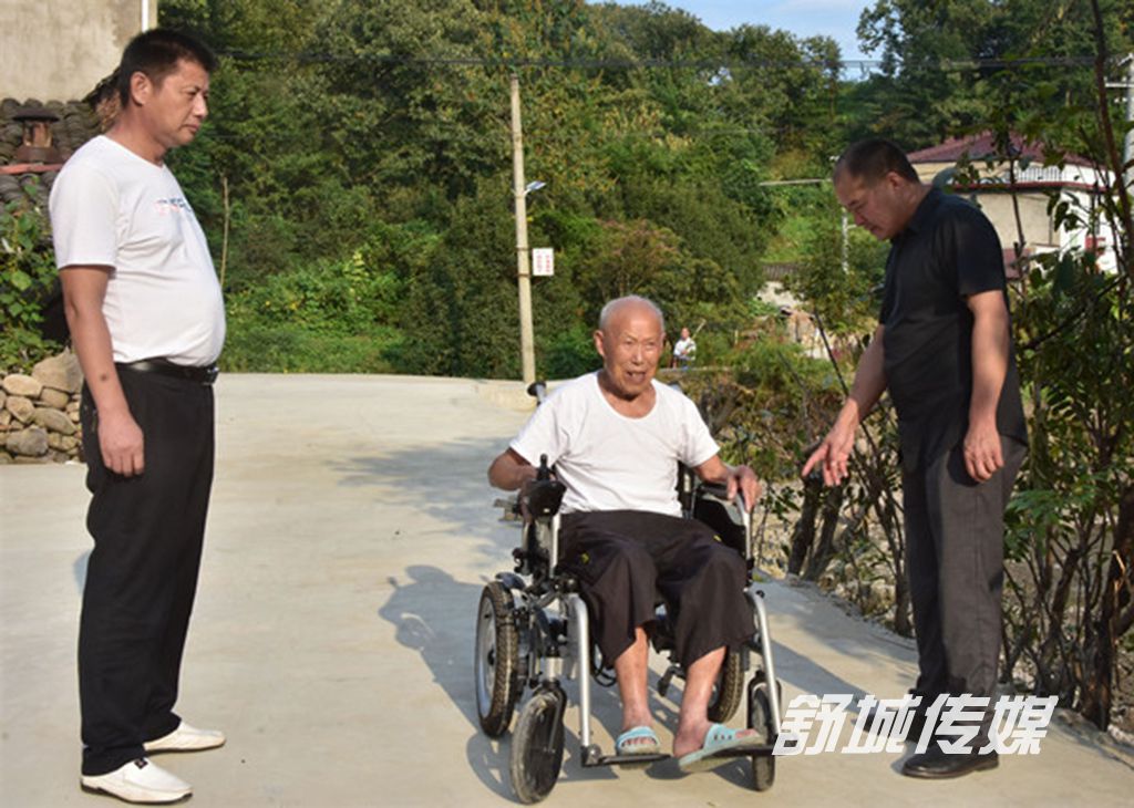 村干部陪同余一和老人在察看硬化后的道路.JPG