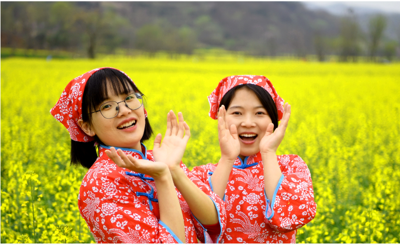 两名采茶归来的姑娘在舒城县舒茶镇沙墩村油菜花海中唱茶歌。